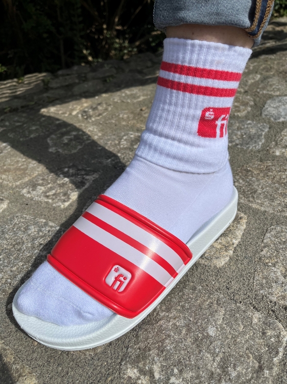 Badelatsche mit weißer Socke mit roten Stichen und rotem Finanz Informatik Logo auf dem Knöchel